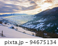 mountain landscape at sunrise. trees on the snow covered hills. sky with glowing clouds 94675134