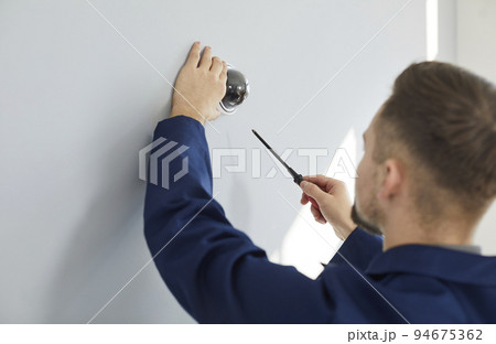 Technician repairing surveillance CCTV dome video camera on wall inside the building 94675362