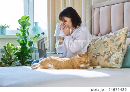 Woman sneezing allergic to domestic cat fur Woman sneezing allergic to domestic cat fur 94675426