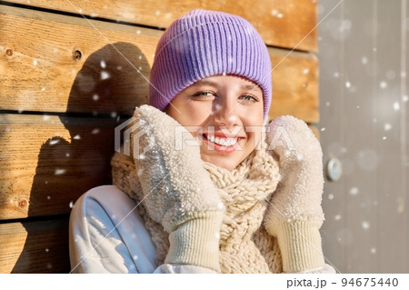Winter portrait of young woman looking at camera with snowflakes on face 94675440
