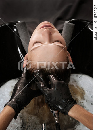 Young woman in a hairdressing salon dyes her hair blond and washing head 94676522