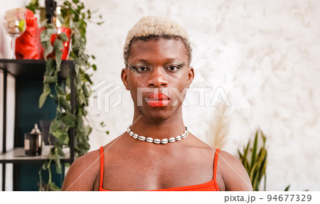 African black transgender model with stylish makeup looking at camera in daytime at home 94677329