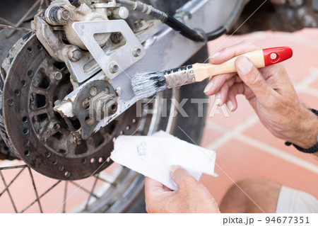 Man painting motorbike with brush at home. Renew old motorbike. Man painting motorbike with brush at home. Renew old motorbike. 94677351