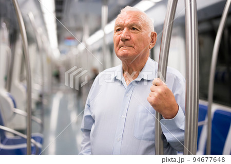 Old man standing in subway car 94677648