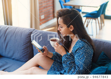 Attractive woman using tablet in modern living room at home. Spending leisure chatting in social network, freelancer working online 94677843