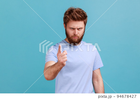 Portrait of strict serious young bearded man warning of mistake, looking at camera with admonishing finger and alarming, giving advice. Indoor studio shot isolated on blue background. 94678427