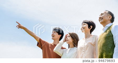 青空を背に並んだ家族　指さし 94679693