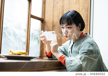 自家製パンケーキの写真を撮影する若い女性 94680092