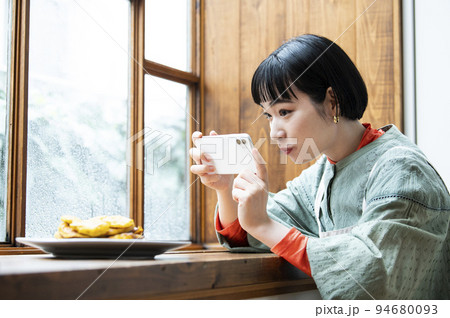 自家製パンケーキの写真を撮影する若い女性 94680093
