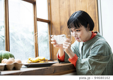 自家製パンケーキの写真を撮影する若い女性 94680102