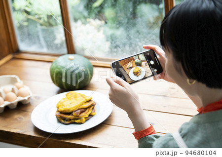 自家製パンケーキの写真を撮影する若い女性 94680104