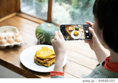 自家製パンケーキの写真を撮影する若い女性 94680105