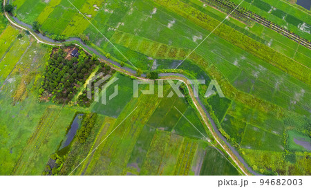 Aerial view of an irrigation canal system in an agricultural area or plantation in northern Thailand. Top view of beautiful green area of young rice fields in spring. Natural landscape background. Aerial view of an irrigation canal system in an agricultural area or plantation in northern Thailand. Top view of beautiful green area of young rice fields in spring. Natural landscape background. 94682003