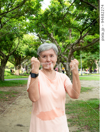 Portrait of happy senior adult elderly asia woman 60s doing winner gesture celebrating clenching fist say yes isolated in the park. 94682274