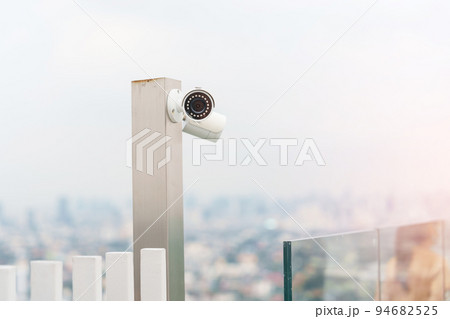 Modern CCTV camera against city and sky background. surveillance, video record and monitoring concept Modern CCTV camera against city and sky background. surveillance, video record and monitoring concept 94682525