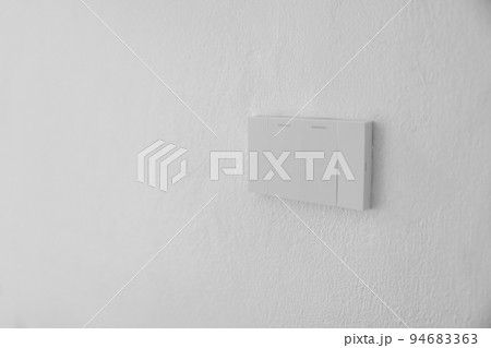 Light switch, Close-up White plastic mechanical switch mounted on a white wall Light switch, Close-up White plastic mechanical switch mounted on a white wall 94683363