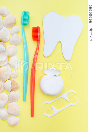 Tooth model, toothbrush and seashells. Yellow background. Flat lay. Top view. Benefits of minerals for dental hygiene. Oral care. Strength of teeth and gums. Vertical. Gum health. Tooth model, toothbrush and seashells. Yellow background. Flat lay. Top view. Benefits of minerals for dental hygiene. Oral care. Strength of teeth and gums. Vertical. Gum health. 94686699