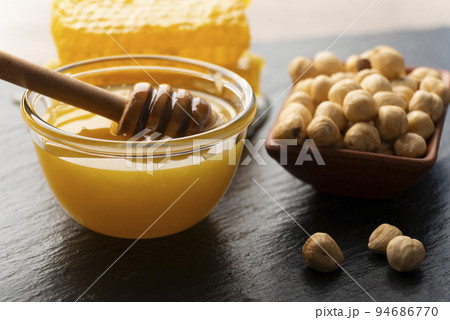 Slate tray with honey hazelnuts and honeycomb on kitchen table 94686770