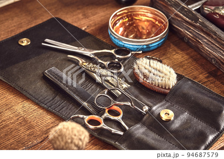 Hairdresser tools on wooden background. Top view on wooden table with scissors, comb, hairbrushes and hairclips, trimmer. Hairdresser tools on wooden background. Top view on wooden table with scissors, comb, hairbrushes and hairclips, trimmer. 94687579