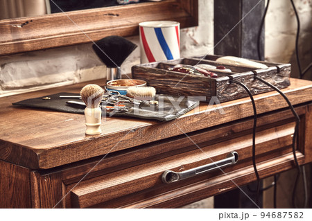 Hairdresser tools on wooden background. Top view on wooden table with scissors, comb, hairbrushes and hairclips, trimmer. Hairdresser tools on wooden background. Top view on wooden table with scissors, comb, hairbrushes and hairclips, trimmer. 94687582