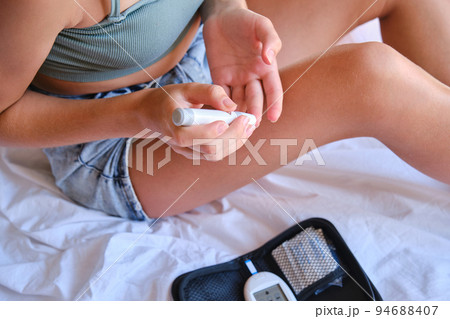 Teenage girl measures blood sugar level on the bed at home. 94688407