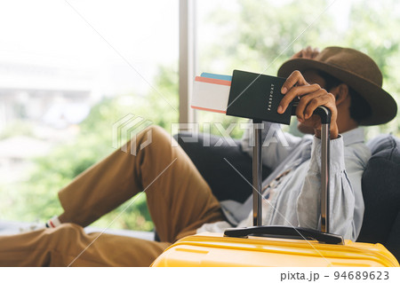 Traveller asian man arm holding luggage handle passport and reservation airplane ticket 94689623