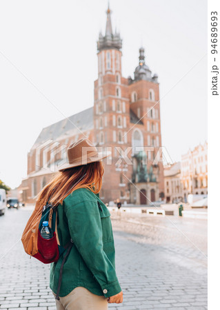 Famous cathedral in sun light, Tourist happy woman on Market Square in Krakow, Traveling Europe in autumn. St. Marys Basilica Famous cathedral in sun light, Tourist happy woman on Market Square in Krakow, Traveling Europe in autumn. St. Marys Basilica 94689693