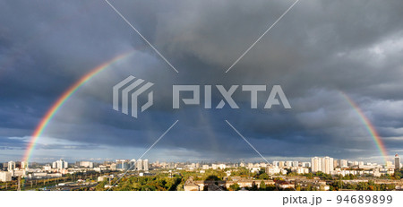 A large rainbow in the cloudy sky over the city after heavy rain. 94689899