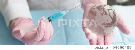 Medical worker hold syringe and miniature world globe in hands Medical worker hold syringe and miniature world globe in hands 94690406