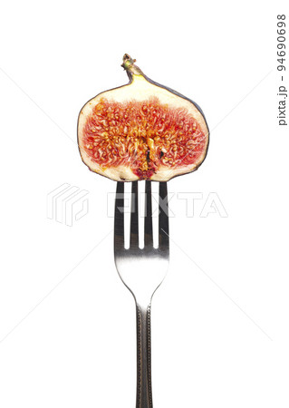 Dark fig on a fork isolated on a white background Dark fig on a fork isolated on a white background 94690698