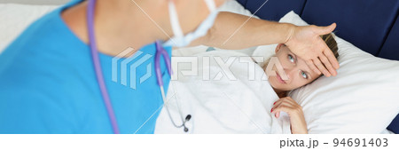 Doctor touches forehead of sick woman in bed Doctor touches forehead of sick woman in bed 94691403