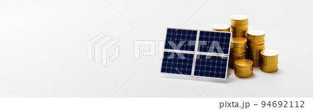 Solar Panel ahead of Stacks of Coins on Gray Background 94692112
