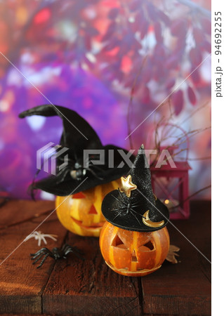 Halloween decorations, Jack-o-lantern pumpkins and a lamp with a burning candle, Halloween celebration, autumn leaves, nature background, evening, festive atmosphere, mystical and magical 94692255