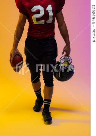 Midsection of caucasian male american football player with neon purple and yellow lighting Midsection of caucasian male american football player with neon purple and yellow lighting 94693621