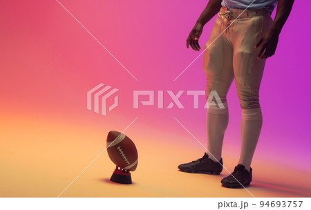 Midsection of african american male american football player with neon pink lighting Midsection of african american male american football player with neon pink lighting 94693757