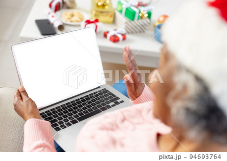 Happy senior african american women wearing santa claus hat and holding laptop with copy space 94693764