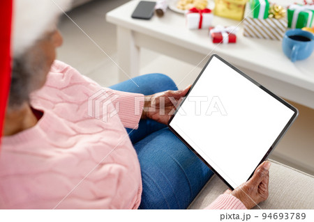 Happy senior african american women wearing santa claus hat and holding tablet with copy space 94693789