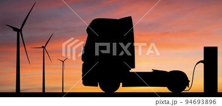 Silhouettes of charging electric truck and wind turbines 94693896