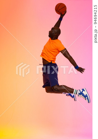 Image of african american basketball player jumping with basketball on pink to orange background Image of african american basketball player jumping with basketball on pink to orange background 94694215
