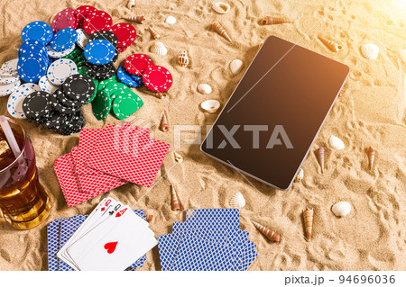 Online poker game on the beach with digital tablet and stacks of chips. Top view Online poker game on the beach with digital tablet and stacks of chips. Top view 94696036