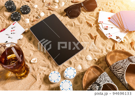 Online poker game on the beach with digital tablet and stacks of chips. Top view Online poker game on the beach with digital tablet and stacks of chips. Top view 94696133