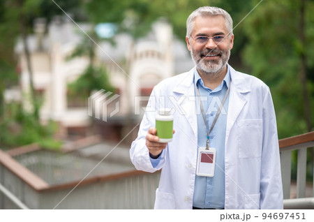 Smiling man in a lab coat with a cup of coffee 94697451