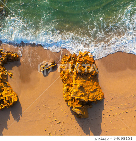 Beautiful landscape with sandy beach and big stones. Beautiful ocean beach with yellow sand, aerial view. Drone view of blue waves and sandy beach with stones.   Portugal. Top view. Drone photography 94698151