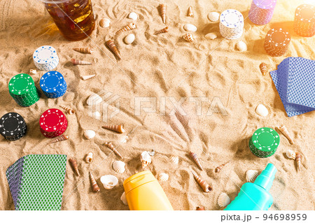 Gambling on vacation concept - white sand with seashells , colored poker chips and cards. Top view 94698959