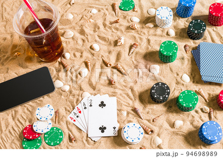 Gambling on vacation concept - white sand with seashells , colored poker chips and cards. Top view 94698989