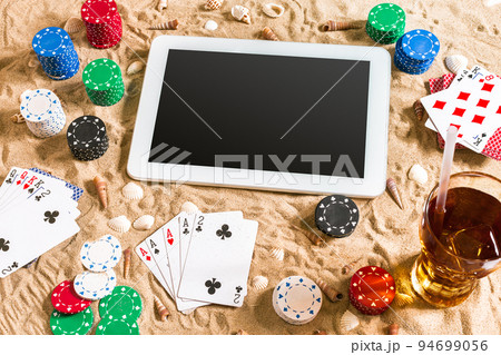 Gambling on vacation concept - white sand with seashells , colored poker chips and cards. Top view 94699056