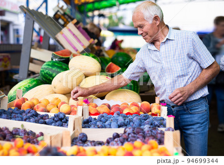 retired european man buying plums peaches nectarine in market retired european man buying plums peaches nectarine in market 94699344