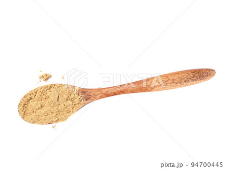 Powder of ground ginger on a wooden spoon over a white background. 94700445