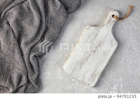 Wooden white cutting room and gray kitchen towel on a light gray concrete table Wooden white cutting room and gray kitchen towel on a light gray concrete table 94701235