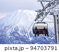 リフトに乗るスノーボーダーと積雪の羊蹄山 (北海道、ニセコ) 94703791